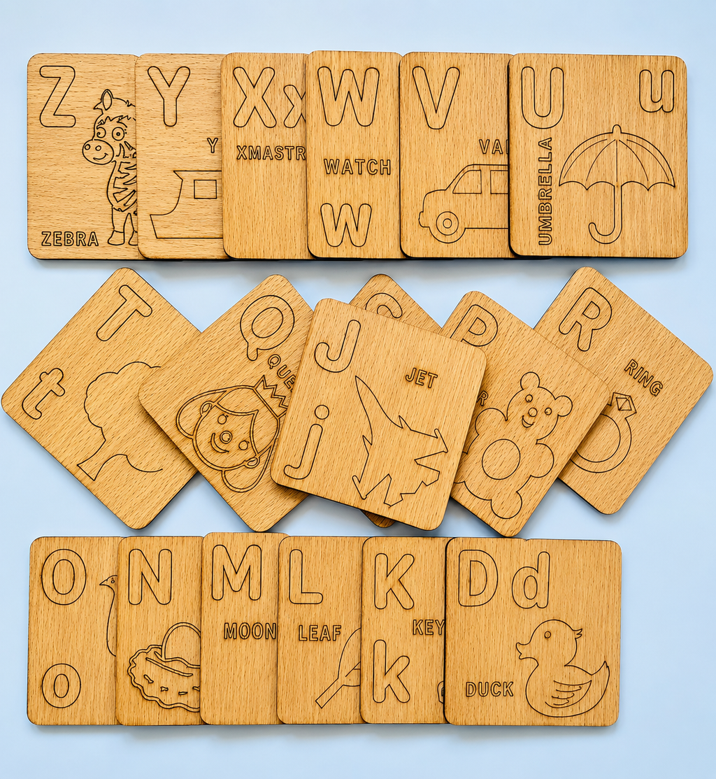 A set of wooden alphabet cards arranged in three rows on a light blue background. Each card shows a different uppercase letter from A to Z, engraved with a corresponding animal or object illustration and word.

